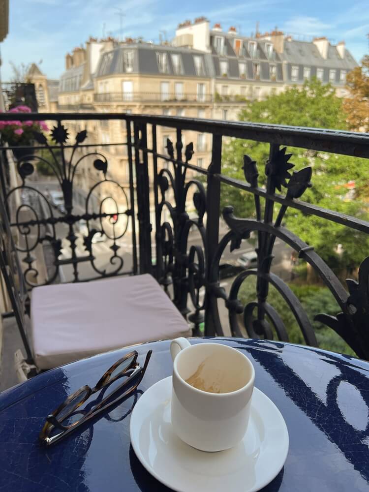 Espresso cup on a cafe table on a Paris hotel balcony overlooking the street at Hotel Residence Henri IV